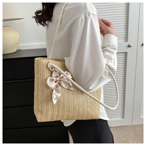 Détail d'un sac cabas en paille avec anse en corde blanche et nœud en foulard de soie