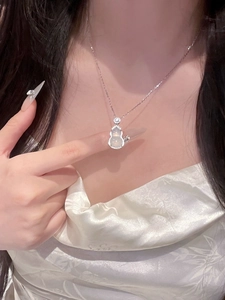 Close-up of a silver gourd pendant necklace with white stone and zircon on a model