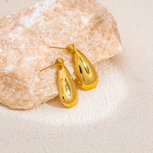 Macro shot of 18k gold plated teardrop earrings on a natural stone textured background