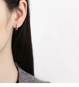 Close-up of 925 sterling silver D-shaped huggie earrings with sparkling crystals