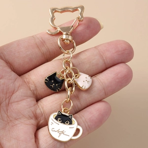 Detail of cute cat paw enamel keychain charms with gold metal rings held on fingers