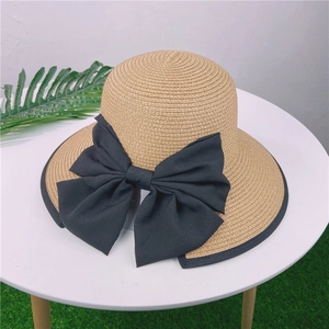 Détail d'un chapeau de paille tressé avec un grand nœud noir et un bord contrasté