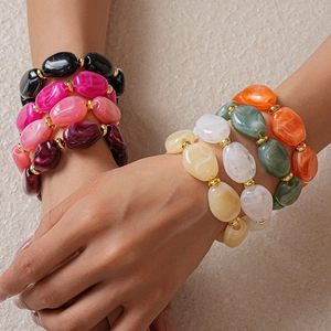 Macro shot of colorful oval resin beads bracelet with golden metal spacers on model