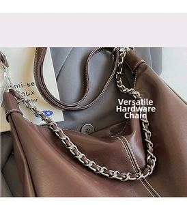 Close-up of brown PU leather hobo bag with bold silver chain and white contrast stitching