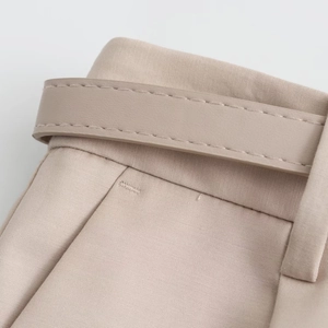 Détail du short plissé beige avec ceinture assortie et coutures de taille précises