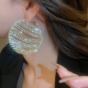 Detailed view of oversized gold hoop earrings with sparkling rhinestones worn by a model