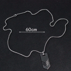 Detailed view of silver arrow pendant on a 60cm box chain with a textured dark background