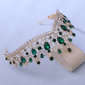 Detailed shot of bridal crown with green emeralds and crystals on a golden frame
