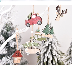 Detail of wooden Christmas ornaments with red truck and deer hanging on white branches