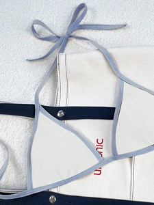 Detail of white triangle bikini top with lavender contrast straps on a soft beach towel