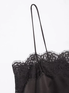 Détail du haut en satin noir avec dentelle délicate et fines bretelles élégantes