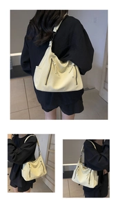 Detail showing the lychee leather texture and vertical zipper of the cream tote bag
