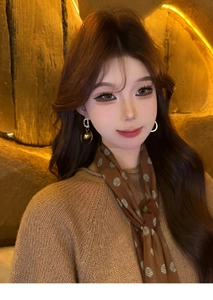 Close-up of golden letter D circular pendant earrings with zircons on a model