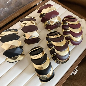 Detail view of elastic geometric bracelets in matte black, burgundy, and gold finish
