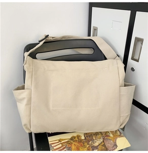 Detail shot of a cream canvas tote bag with side pockets placed on a black vintage chair