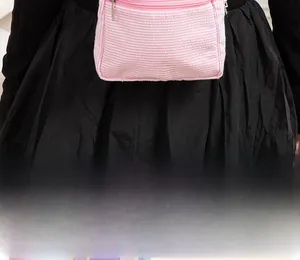 Close-up of pink and white striped seersucker small backpack worn as a waist bag