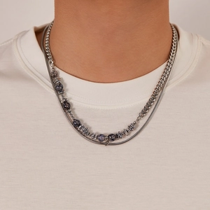 Close-up of double-layer silver snake chain and Cuban necklace with dark stones on model