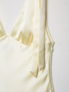 Detail of invisible side zipper and smooth satin texture on yellow midi dress