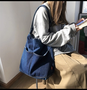 Deep blue denim tote bag with front pockets shown in a casual lifestyle setting
