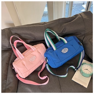 Pink and blue duffel bags with striped handles and detachable straps on a sofa