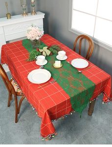 Detail of red plaid tablecloth with green lace runner and festive colorful tassel edges