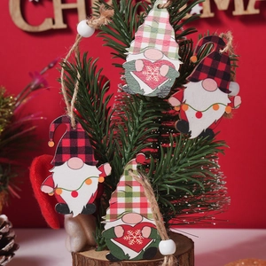 Hanging wooden Christmas gnome ornaments with plaid hats and beads on a festive tree