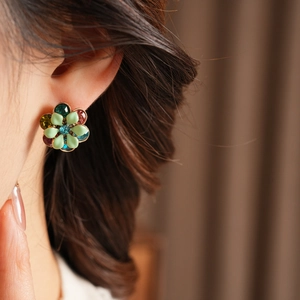 Detail view of vintage floral stud earrings with blue rhinestones and colorful enamel petals