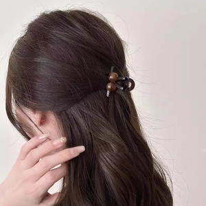 Detail of dark cherry hair claw clip with brown spherical beads worn on hair