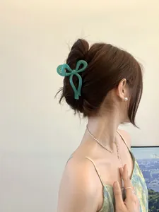 Glossy green bow hair claw clip styled on a woman's hair for an elegant look