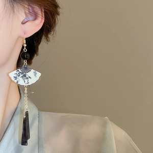 Détail de boucles d'oreilles en éventail avec motif bambou et longs glands élégants