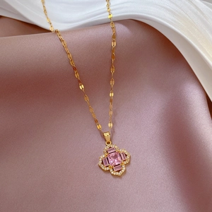 Titanium steel gold necklace with pink stone clover pendant on luxury silk background