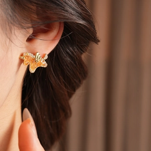 Close-up of elegant gold horse stud earring with orange gemstone on model ear