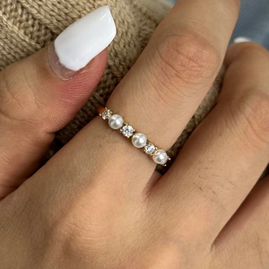 Primo piano di un elegante anello in acciaio dorato con perle e zirconi brillanti