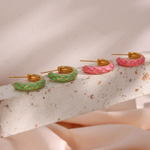 Detail showing two pairs of C-shaped gold metal earrings with colorful enamel grid patterns
