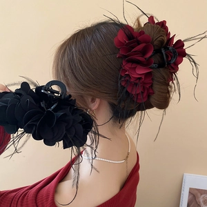 Detailed view of elegant wine red and black flower hair claws with soft feather accents