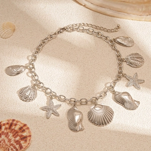 Macro detail of silver starfish and seashell charms on a textured metal chain