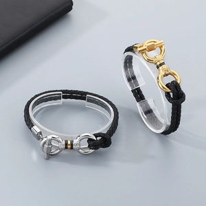 Close-up of braided leather bracelets with gold and silver horseshoe T-bar clasps