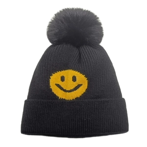 Detailansicht der schwarzen Strickmütze mit gelbem Smiley und flauschigem Bommel