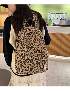 Close-up of leopard print corduroy backpack on model in a casual indoor setting