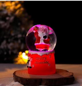 Close-up of a festive Christmas crystal ball with Santa Claus inside a red resin base