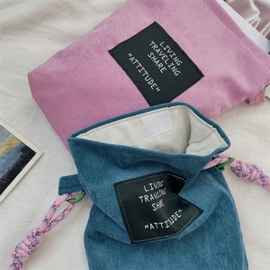 Detailed texture of corduroy drawstring pouches in pink and cyan with woven ropes