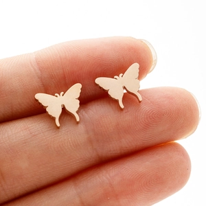 Rose gold butterfly stud earrings shown on finger for scale with elegant metal wings