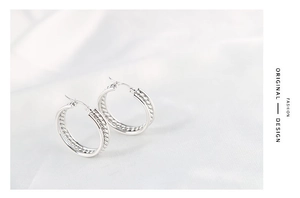 Detailed close-up of double-layered silver hoop earrings with twisted rope texture