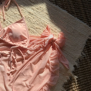 Detail of pink three-piece bikini set with mesh ruffle skirt and side bow accents