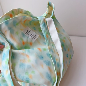 Detail view of cotton tote bag with mint green watercolor print and white handles