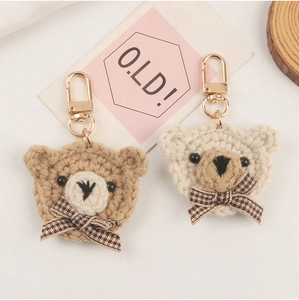 Detail of handmade crochet bear keychains with plaid bows and golden lobster clasps