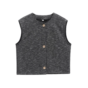 Dettaglio di un gilet in tweed grigio con tre bottoni dorati decorativi sul davanti
