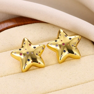 Close-up of star-shaped gold earrings with colorful zircon stones in a beige jewelry box