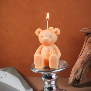 Detailed close-up of a pink bear candle with bow and flower on a silver base