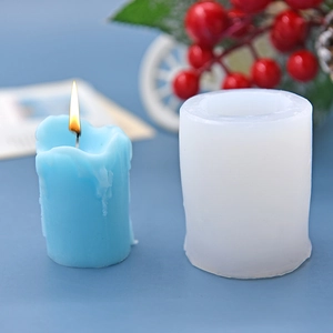 Cylindrical silicone candle mold with finished blue candle in a festive winter scene
